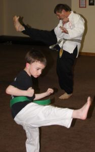 Chris Devine shows the beginner class a kick combination as a young student follows his instruction. Jean Schurman photo